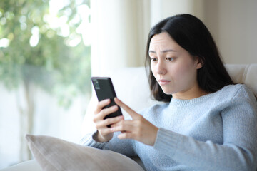 Disgusted asian woman watching media on phone