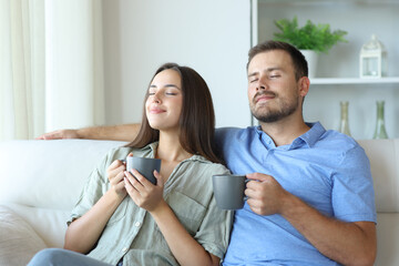 Happy couple drinking and breathing relaxing at home