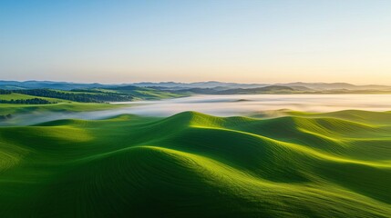 Obraz premium Aerial landscape abstract background idea. A serene landscape showcasing rolling green hills under a clear blue sky at sunrise.