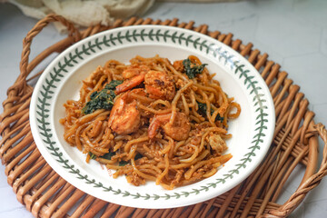 A plate of fried noodle with some vegetables and prawns. 