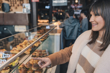 Woman choosing food from display in a busy market hall