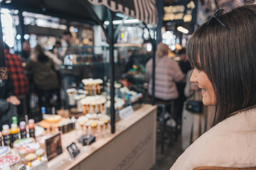Woman choosing pastries at food market stall smiling