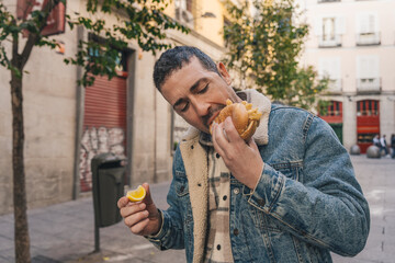 Man eating street food sandwich with lemon in the city