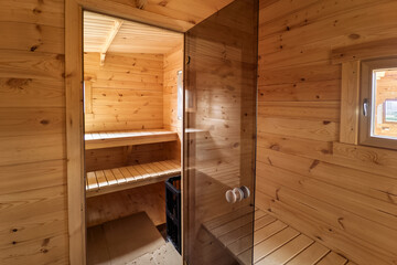 Interior of Finnish sauna, classic wooden sauna with hot steam. Russian bathroom. Relax in hot sauna with steam. Wooden interior baths, wooden benches and loungers accessories for sauna, spa complex.