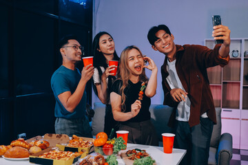 Happy young friends group having lunch at home. Asia family party eating pizza food and laughing enjoying meal while sitting at dining table together at house. Celebration holiday and togetherness.