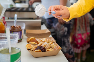 Dutch Mini Pancakes Poffertjes. Fluffy mini pancakes that are served with a mess of powdered sugar and jam. Typical Dutch poffertjes - tiny pancakes- being prepared during street food festival.