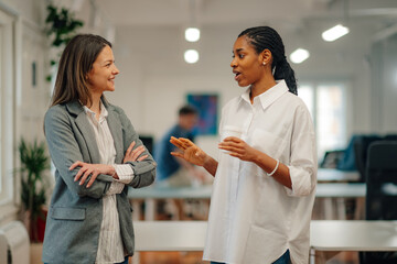 Two businesswomen talking during coffee break in modern office
