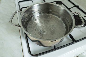 Water is boiling in a stainless steel pot on a gas stove.