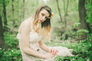 Girl in a white dress in a beautiful fairy-tale summer forest