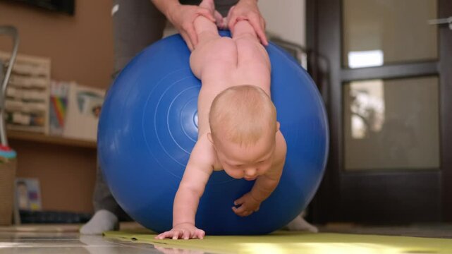 Massage for little child, infant baby gets exercise therapy on a fitness ball, stretching muscles and improving coordination, early childhood development, 3 6 months, pediatric therapy, baby care.