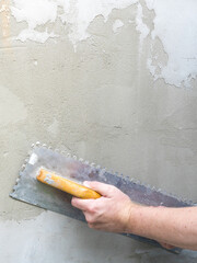 Person is using a trowel to apply a layer of plaster to a wall