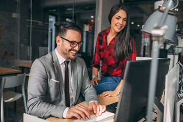 Happy busy executive people working together in office. Female manager showing financial results to colleague at work. Two professional team business man and woman using PC compu at corporate meeting.