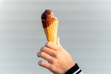 Female hand with a horn of ice cream on light white background