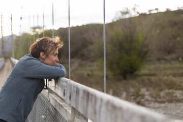 Woman leaning on bridge railing enjoying nature view in new zealand