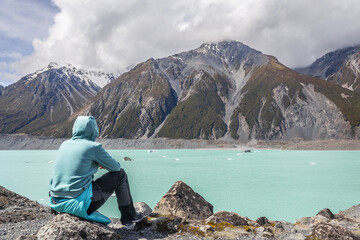 Hiker resting and admiring the hooker lake in mount cook national park, new zealand