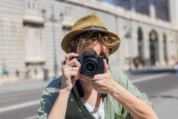 Tourist taking photos in madrid city center with royal palace in background