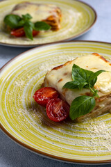 Italian lasagna on a blue plate with a fork and basil leaf