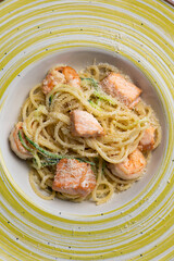 Spaghetti with salmon and herbs in a bowl on the table.
