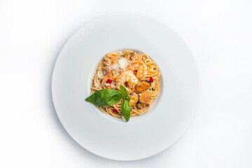 Spaghetti with shrimps and basil on a white plate.