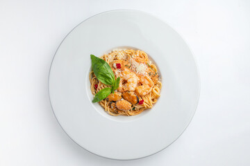 Spaghetti with shrimps and basil on a white plate.