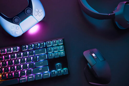 Top down view of various gaming accessories laying on table. Colorful illuminated devices. - Powered by Adobe