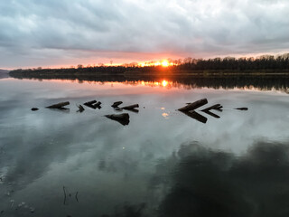 A stunning sunset casts vibrant colors over a serene lake, where birds gracefully float on the mirrorlike surface of the water, highlighting the beauty of nature at dusk