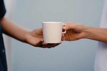 Hands exchanging white cup, symbolizing connection and shared mo