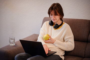 Woman Working on Laptop While Eating an Apple