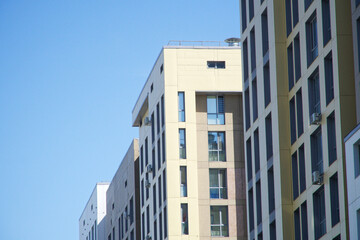 Obraz premium A modern multi-story building facade with windows and air conditioners, ideal for illustrating contemporary city architecture or real estate concepts. Photo