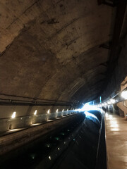Obraz premium A dark and mysterious tunnel, which is dimly illuminated by a few flickering lights mounted on the walls, creates an eerie atmosphere that greatly enhances the overall sense of adventure