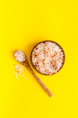 Coarse pink salt in wooden bowl and spoon and spilled salt. Cooking or spa concept