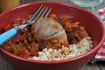 Paupiette de veau avec du riz accompagnée d'une compotée de poivrons et tomates servie dans une assiette avec une fourchette en gros plan