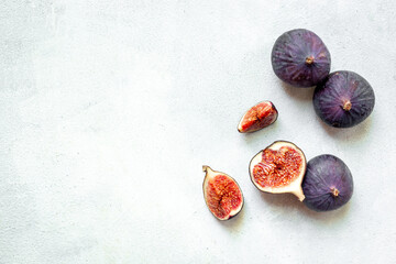 Whole and cut fresh ripe figs on stone table. Top view