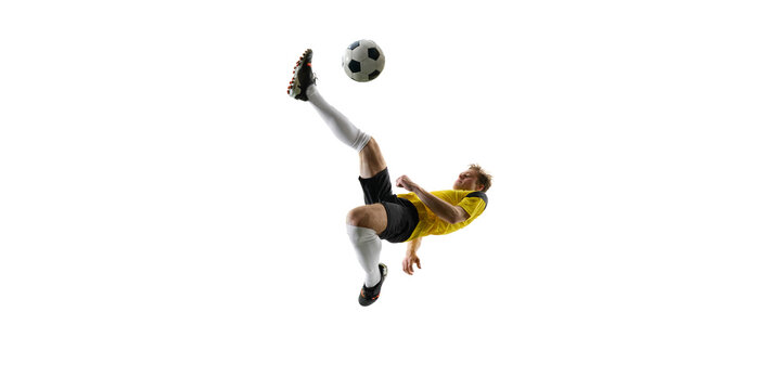 Focused man, soccer player executing overhead kick, dynamically kicking ball in air and falling down against white background. Concept of sport, action, competition, game, active lifestyle. Ads