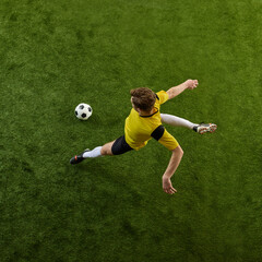 Top view dynamic image of determined young man, soccer player in motion on green stadium, controlling ball, playing. Concept of sport, action, competition, game, active lifestyle. Ads © master1305