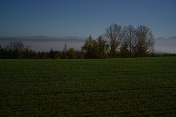夜霧で霞む北海道美瑛の丘陵地帯と星空