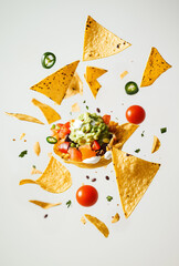 Levitating nachos and guacamole with spices, tomatoes and jalapeno 