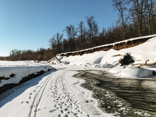 A snowy road, adorned with clear and distinct tire tracks, creates a stunning winter scene that perfectly embodies the cold seasons innate beauty, tranquility, and undeniable charm
