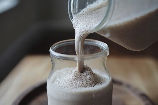Creamy Smoothie Being Poured Into a Glass with Foam on Top