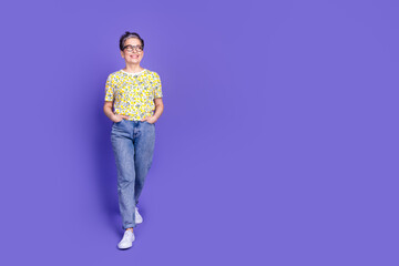 Stylish mature woman wearing floral print blouse, standing against colorful purple backdrop,...