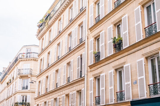 Elegant Light-Colored Building with Wrought Iron Balconies and White Shutters