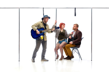 Street musician playing guitar while woman interacts with businessman seated with briefcase against...
