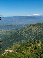 A breathtaking view showcasing a majestic mountain range, beautifully framed by lush green trees and impressive mountains stretching into the distance, creating a stunning natural landscape
