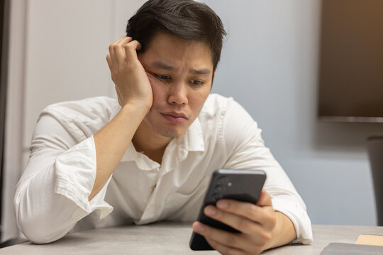 close up asian employee man feeling bored and sleepy when playing smartphone for lifestyle people concept