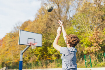 Back view of basketball player playing basketball. Throwing the ball at playground scoring a point....