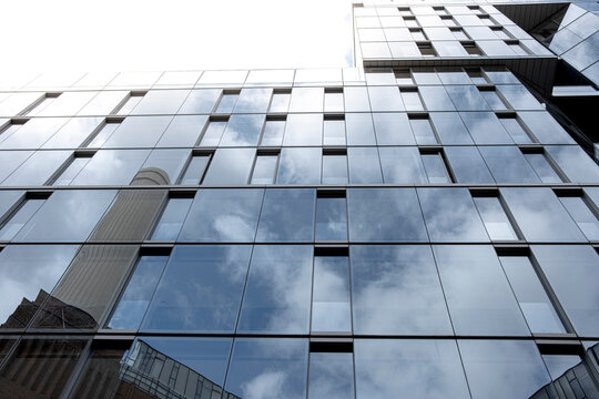 Windows reflecting a cloudy sky over an urban high-rise, contemporary architecture.