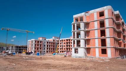 Large construction site with buildings under construction and multi-storey residential homes...