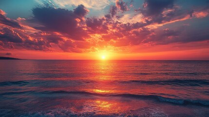 Obraz premium The horizon bursts with stunning colors as the sun descends into the ocean, illuminating the sky with warm tones. Waves gently lap against the shore, creating a peaceful atmosphere