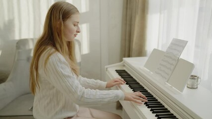 Teenage girl practicing piano at home. Focused young cute girl having fun playing electric piano. Musician teen student teaching music lesson. A quiet person practices the piano