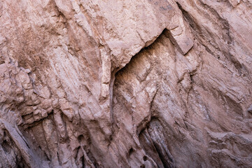 Close-up view of textures and patterns of a weathered rock surface within a canyon. The rock exhibits layers, cracks, and variations in color. Shot in Iran, Middle East.
